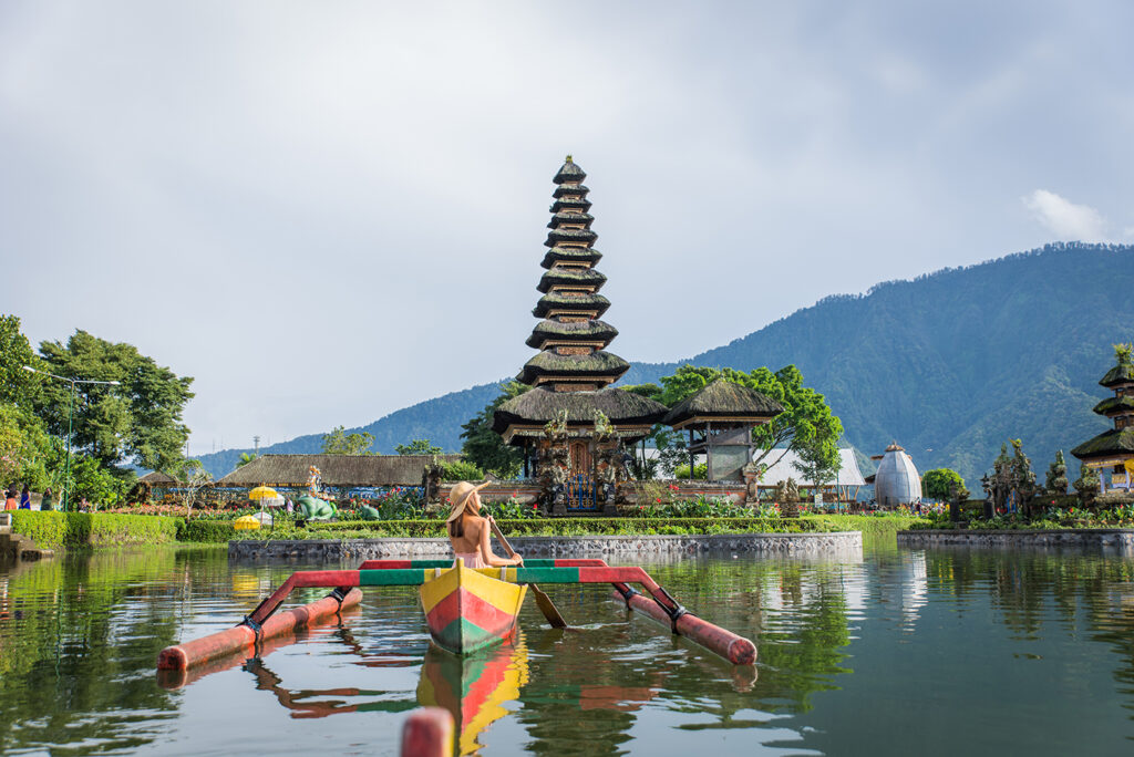 oung woman traveler paddling on a wooden boat at Pura Ulun Danu