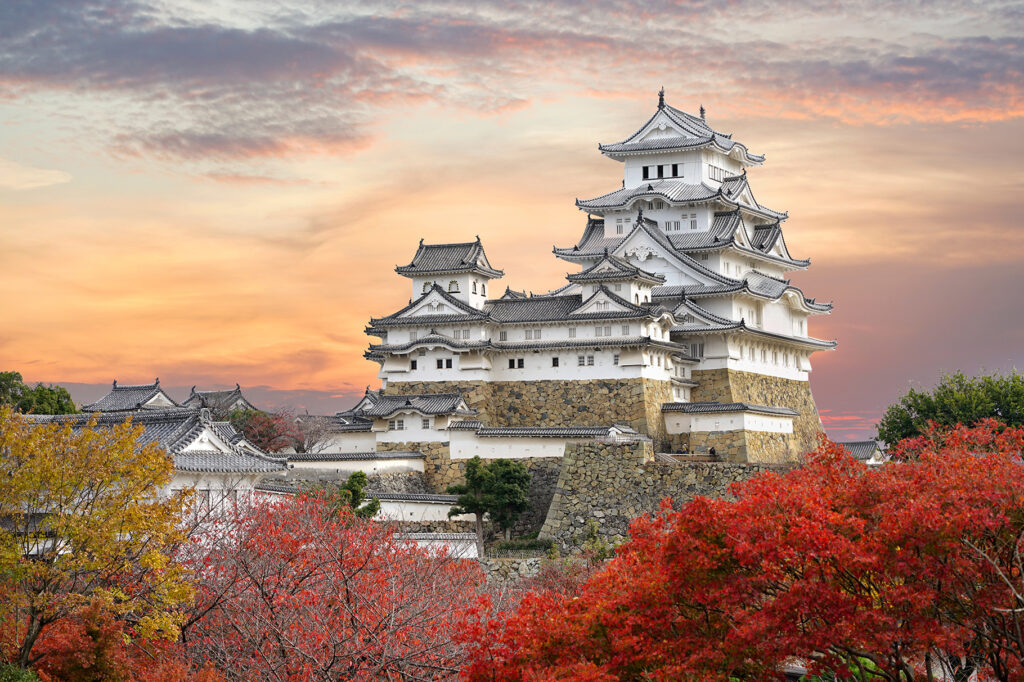 Himeji Castle and red maple leaves in evening sunlight
