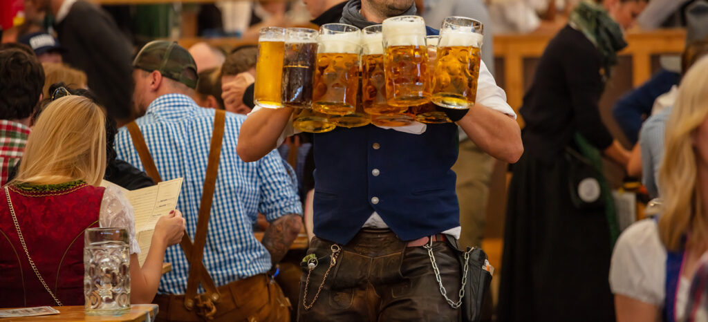 Oktoberfest, Munich, Germany. Waiter with traditional costume serving beers, closeup view