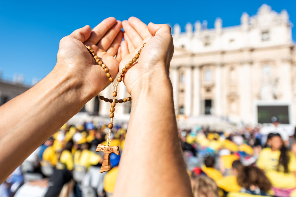Closeup of hands holding wooden handmade Italian cross